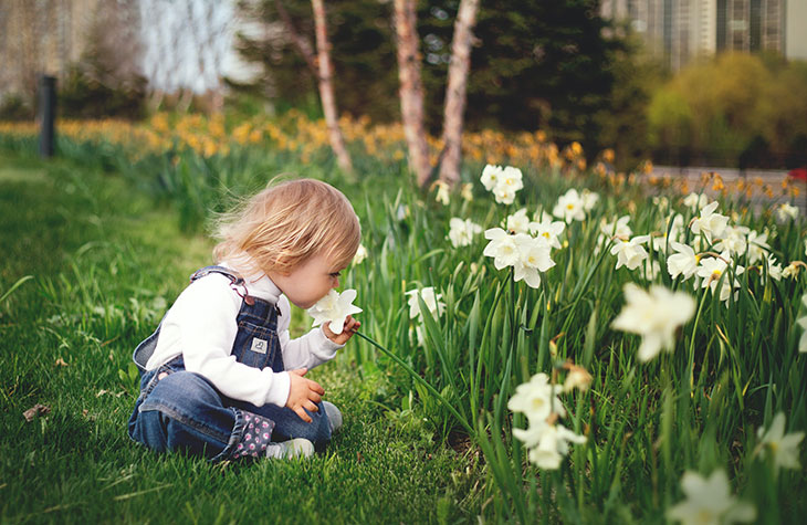 Mädchen riecht an Blume